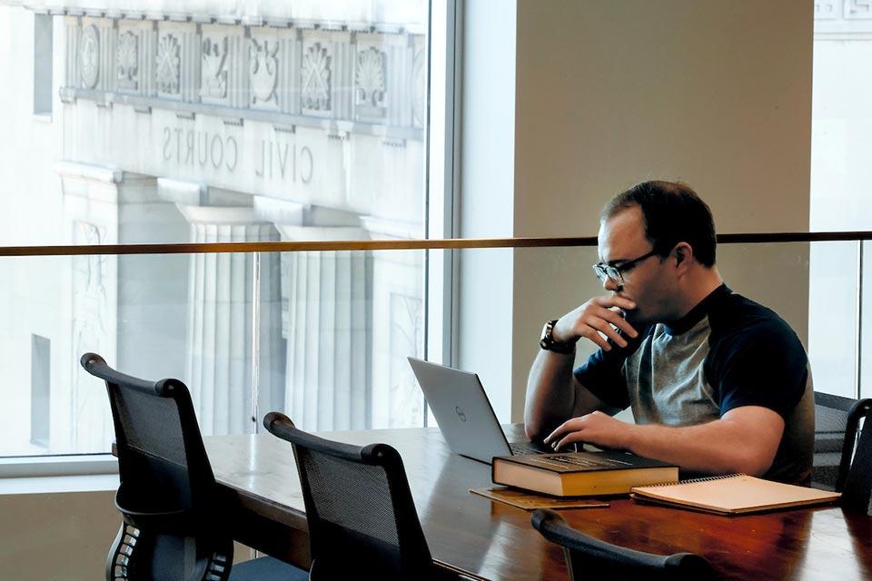 A student sits in front of a window that looks out over St. Louis city Civil Courts